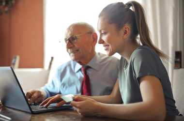 woman helping an old man with the computer