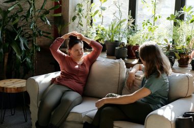 Young woman with a disability sitting on a couch with another woman having a conversation